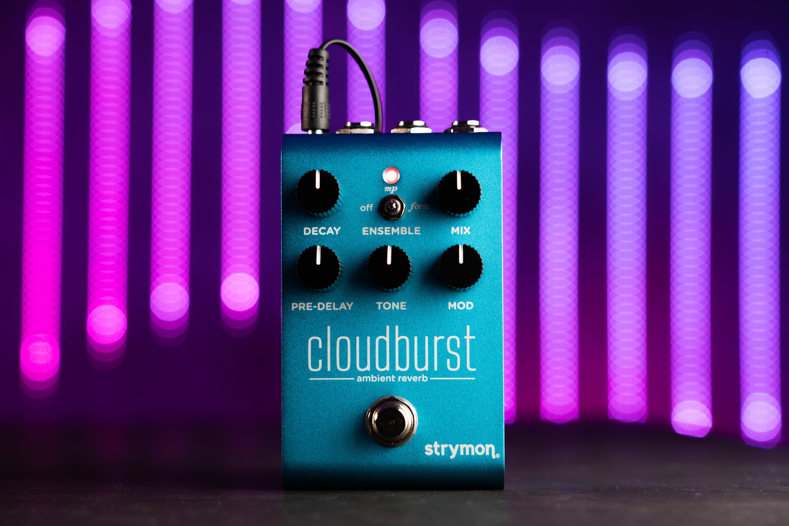 Cloudburst pedal standing up right against blue, pink, and purple LED lights