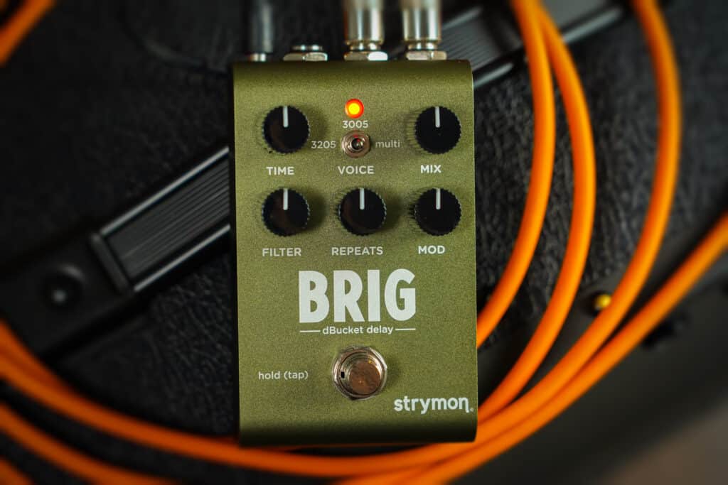 Brig resting on top of an amp with an orange instrument cable.