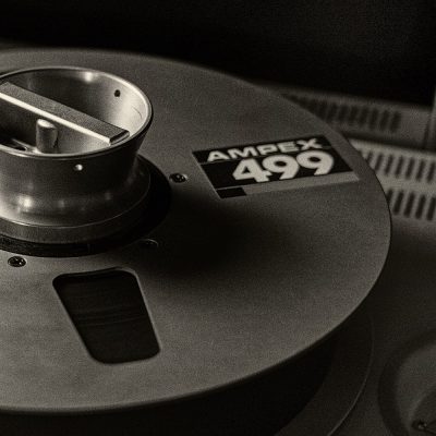 Closeup black and white photo of 2 inch tape on vintage tape machine.